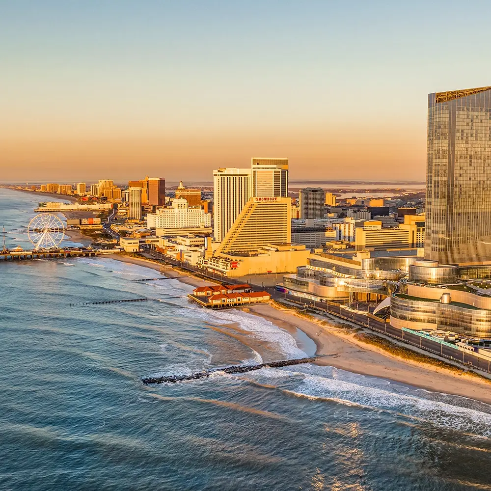 New Jersey An aerial view of the Atlantic City skyline and beach at sunset, featuring the Steel Pier Ferris wheel and large resort hotels along the coastline.