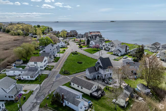 clinton-ct An aerial view of a coastal neighborhood in Clinton, Connecticut, featuring houses near the waterfront.